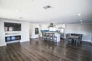 Living area with dark wood finished floors, crown molding, and recessed lighting