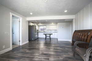 Living area down featuring recessed lighting, dark wood finished floors, and a textured ceiling