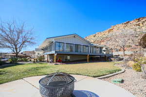 East side of house with an outdoor fire pit, a yard, and a west sun shaded deck