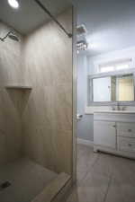 Full bathroom featuring a shower stall, vanity, and light tile patterned flooring