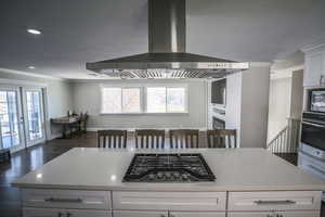 Main Kitchen featuring white cabinetry, crown molding, light stone countertops, stainless steel appliances, and dark wood-type flooring
