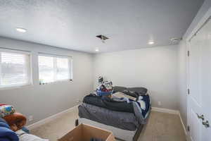 Carpeted bedroom featuring a textured ceiling and recessed lighting