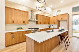 Kitchen featuring light stone countertops, a kitchen breakfast bar, light wood-style flooring, and a kitchen island with sink