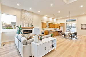 Living area with a stone fireplace, light wood-style flooring, and a chandelier