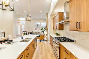 Kitchen featuring stainless steel appliances, light stone countertops, light wood-style flooring, and wood finish cabinets