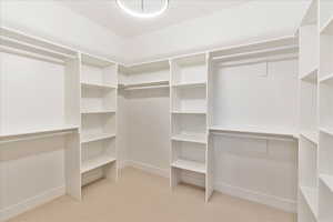 Walk in closet with light colored carpet