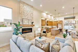 Living area with light wood-style floors, a stone fireplace, and a chandelier
