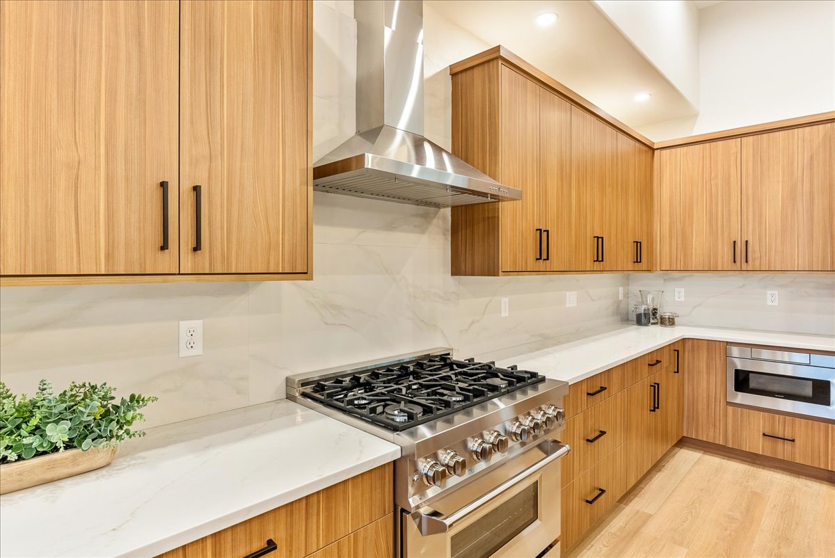 Kitchen featuring stainless steel appliances, light stone counters, tasteful backsplash, and modern cabinets