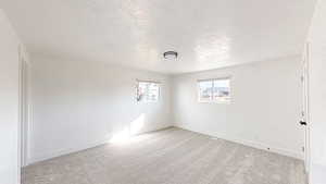 Empty room featuring a textured ceiling and light carpet