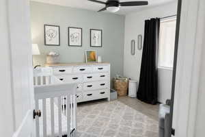 Bedroom featuring a nursery area, light wood-style flooring, and a ceiling fan