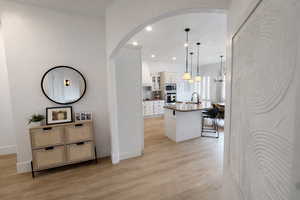 Hall featuring recessed lighting, light wood finished floors, and arched walkways