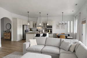 Living area featuring arched walkways, light wood-style flooring, and a chandelier