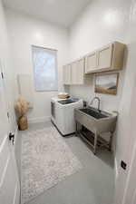 Laundry room featuring independent washer and dryer, cabinet space, concrete flooring, and a textured wall