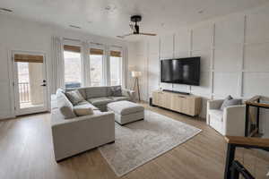 Living area featuring a decorative wall, light wood-type flooring, and ceiling fan