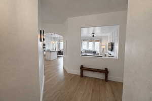 Hall featuring a textured wall, arched walkways, and light wood-style floors