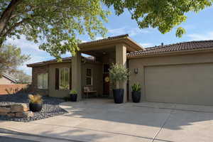 View of front facade with stucco siding, driveway, a tile roof, and a garage