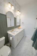 Bathroom with double vanity and light marble finish floors