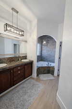 Bathroom with a bath, light wood-style flooring, hanging lights, and double vanity