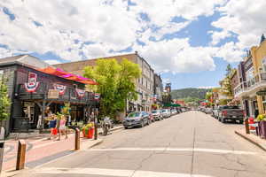 View of asphalt street featuring sidewalks, curbs, and street lights