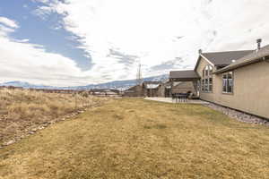View of green lawn with a patio area and a mountain view