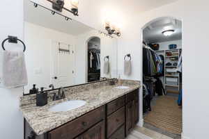 Full bathroom featuring a spacious closet and double vanity