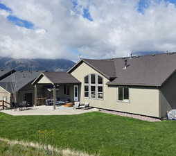 Rear view of property featuring a lawn, a shingled roof, a patio area, outdoor lounge area, and a mountain view