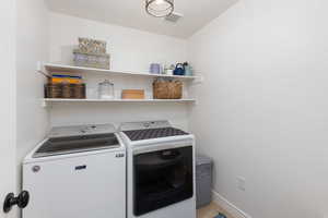 Laundry area featuring separate washer and dryer and baseboards