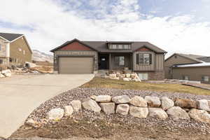Craftsman house with board and batten siding, concrete driveway, a porch, a garage, and a shingled roof