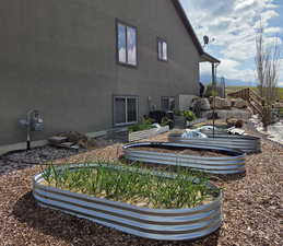 Rear view of house featuring a vegetable garden and stucco siding