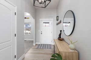 Entryway featuring light wood-style flooring, hanging lights, and arched walkways
