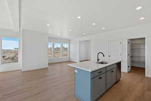 Kitchen with gray cabinetry, light wood-style flooring, a kitchen island with sink, recessed lighting, and open floor plan