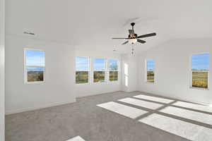 Carpeted spare room featuring ceiling fan and lofted ceiling