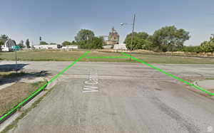 View of asphalt road featuring curbs and street lighting