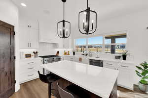 Kitchen with light stone counters, a breakfast bar, light wood-type flooring, backsplash, and a kitchen island