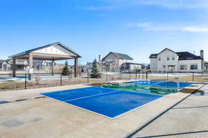 View of tennis court with a residential view and a patio area