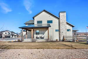 Rear view of house with covered porch, a chimney, board and batten siding, and a metal roof