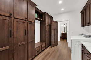 Laundry area with light wood finished floors, cabinet space, recessed lighting, and washer and clothes dryer