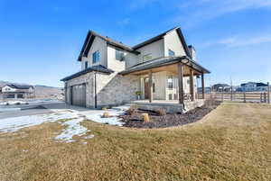 Rear view of property with a standing seam roof, covered porch, stone siding, a garage, and concrete driveway