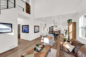Living room with wood finished floors, a high ceiling, and recessed lighting