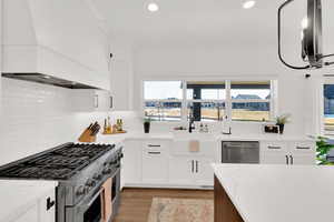 Kitchen with stainless steel appliances, light stone counters, dual tone cabinetry, light wood finished floors, and recessed lighting