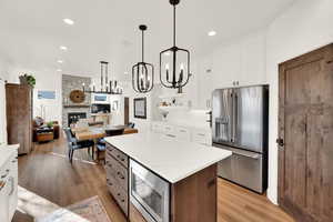 Kitchen featuring dual tone cabinets, a center island, stainless steel appliances, open floor plan, and a stone fireplace
