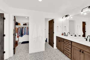Bathroom featuring a walk in closet, double vanity, and recessed lighting