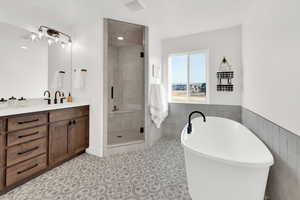 Bathroom featuring a shower stall, a freestanding bath, tile walls, vanity, and a wainscoted wall