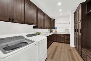 Laundry room featuring cabinet space, light wood finished floors, washer and clothes dryer, and recessed lighting