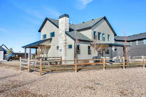 Rear view of property featuring a fenced front yard, a chimney, a patio area, and roof with shingles