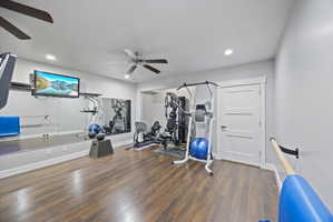 Exercise room with ceiling fan, dark wood-style floors, and recessed lighting
