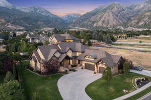 View of front of home with stone siding, driveway, a mountain view, a garage, and roof with shingles