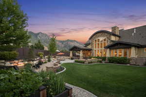 Yard at dusk with a patio area, a fenced backyard, and a mountain view
