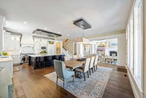 Dining room featuring dark wood-style floors, hanging lights, and a lit fireplace