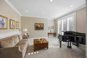 Carpeted living area featuring ornamental molding and recessed lighting